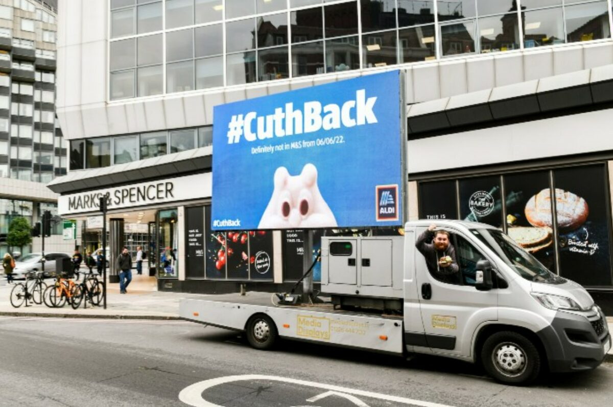 Supermarket giant Aldi has marked the launch of its brand new Nando's inspired range with a tongue-in-cheek stunt aimed at the restaurant chain, similar to another cheeky stunt the supermarket launched over the return of it's Cuthbert the Caterpillar cake (depicted here as a blue background ad-van outside an M&S).