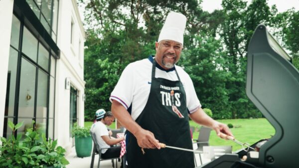 John Barnes, clad in chefs gear, at thr barbecue. Footballing legend John Barnes has teamed up with plant-based food firm This to launch a new summer BBQ banger ahead of the Euros.